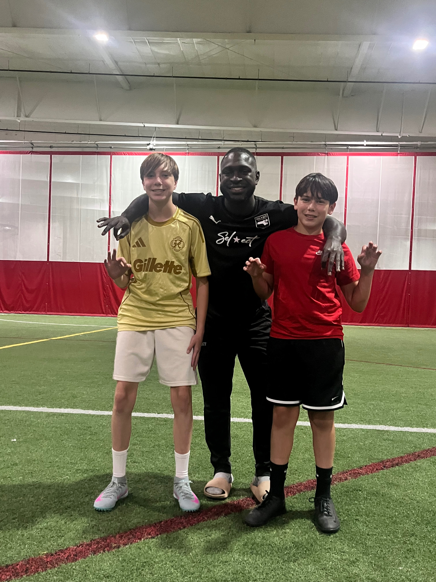 Coach Mojo on the indoor pitch with two of his players after a session